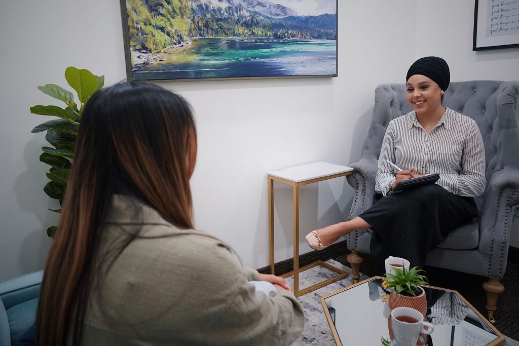 Two women in a cozy office setting engage in a friendly and casual meeting.